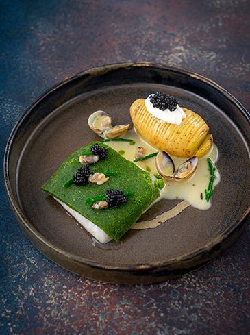 Turbot with herb crust with hasselback potatoes, clams and butter sauce