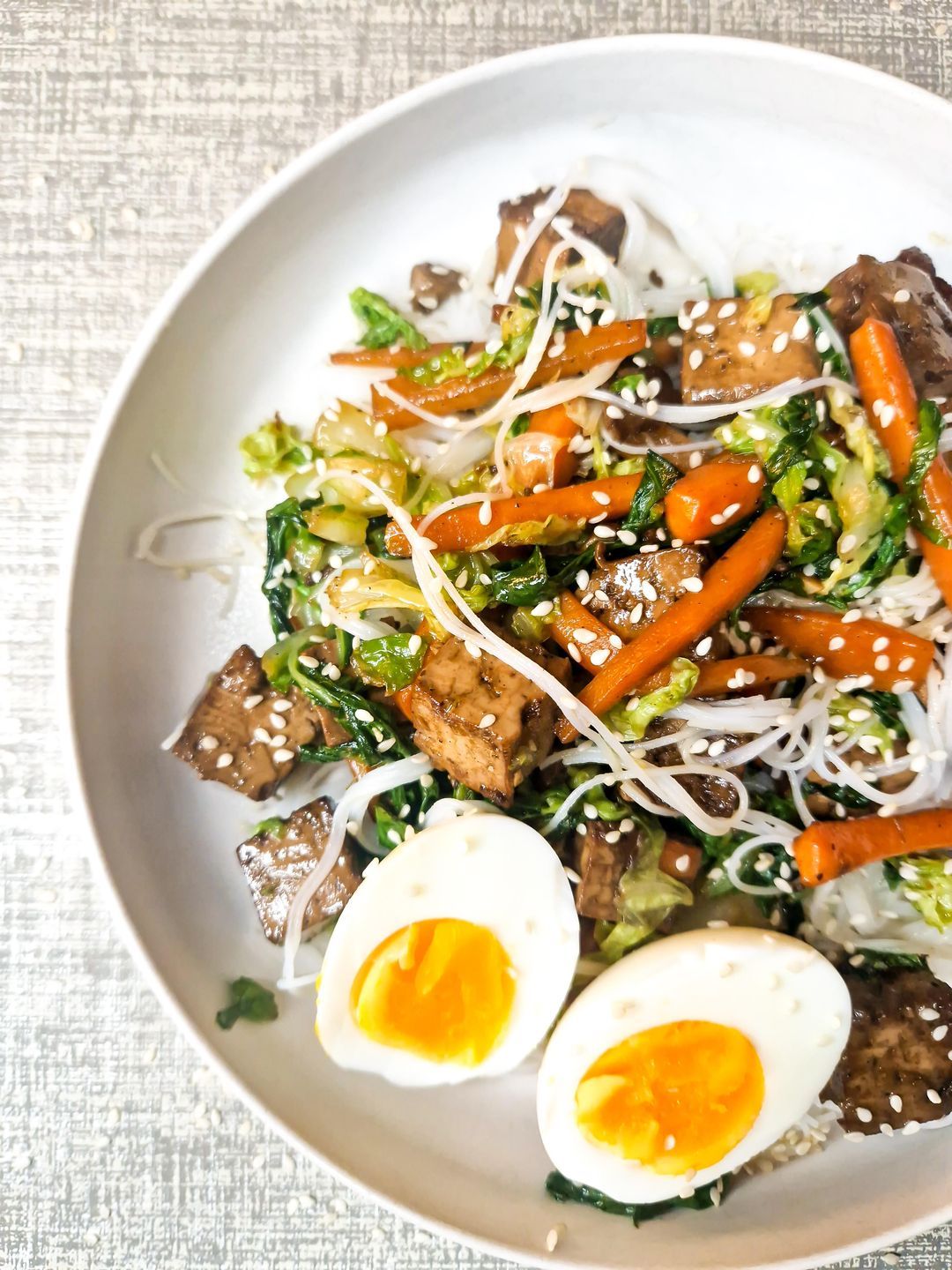 Marinated tofu with noodles, fried vegetables and a soft boiled egg